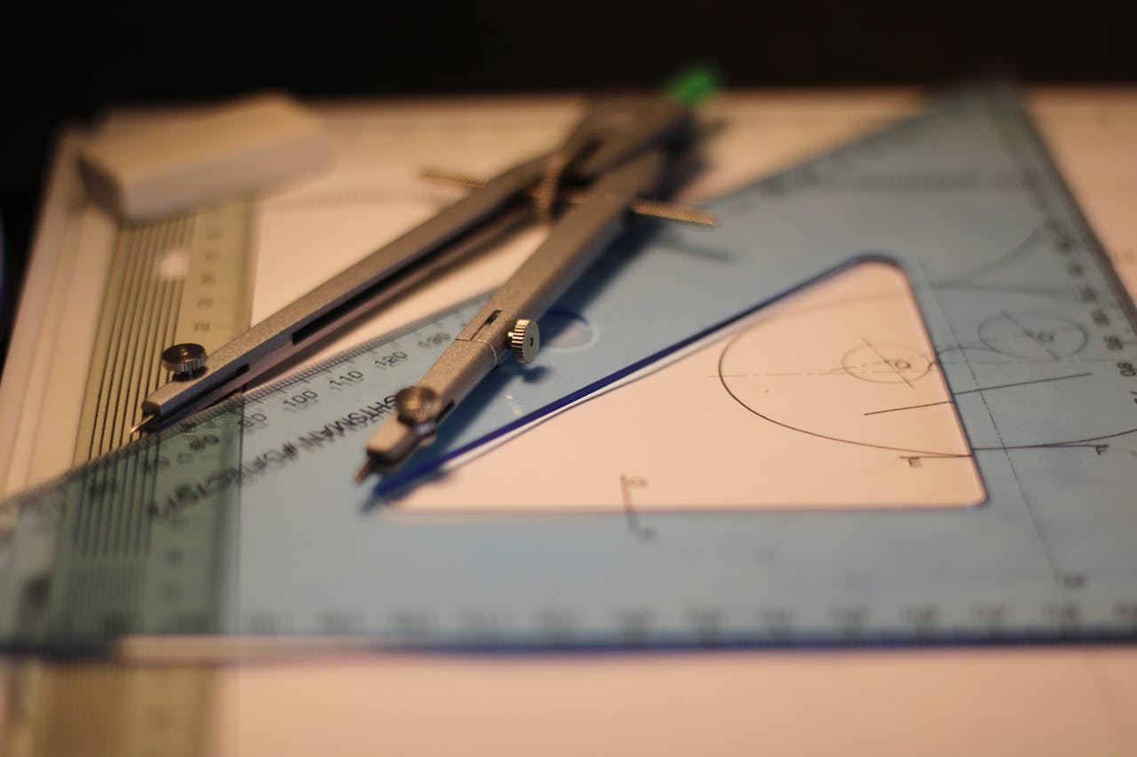 Precision drafting tools including compass and set square on a sketchpad.