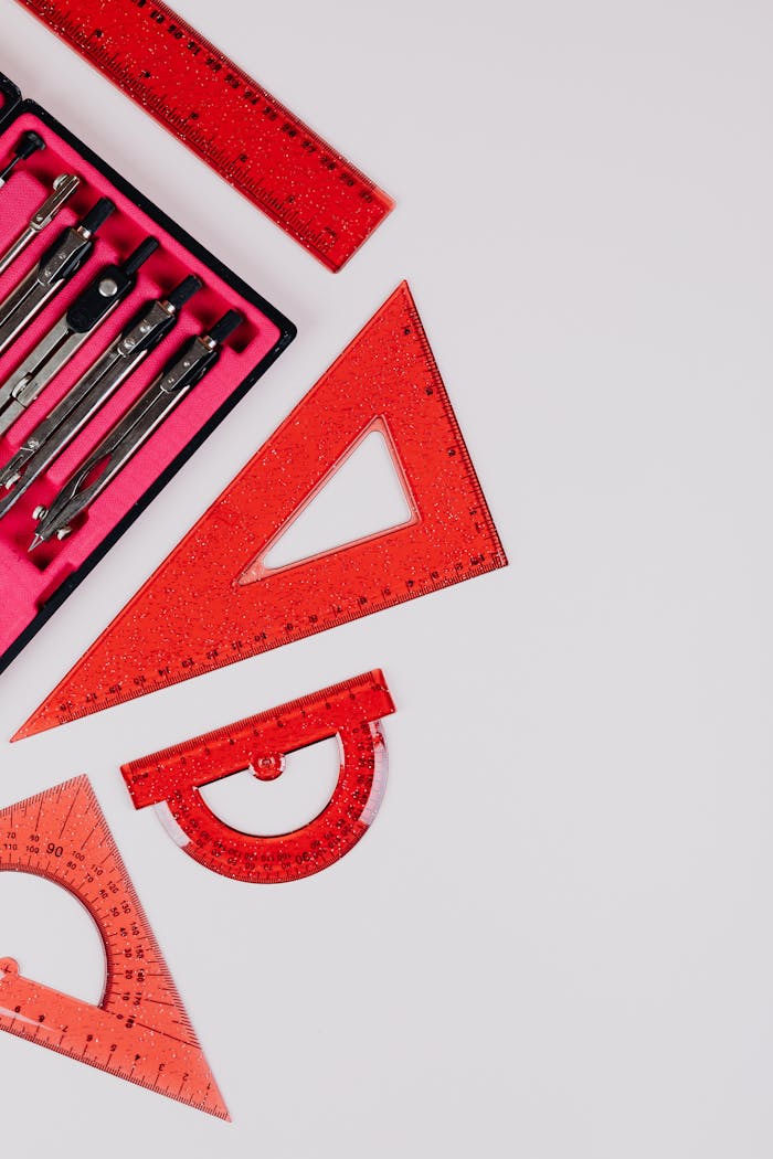A flat lay of red geometric tools including rulers and protractors on a white surface.